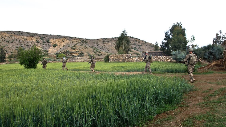 US Troops walking across an open field.